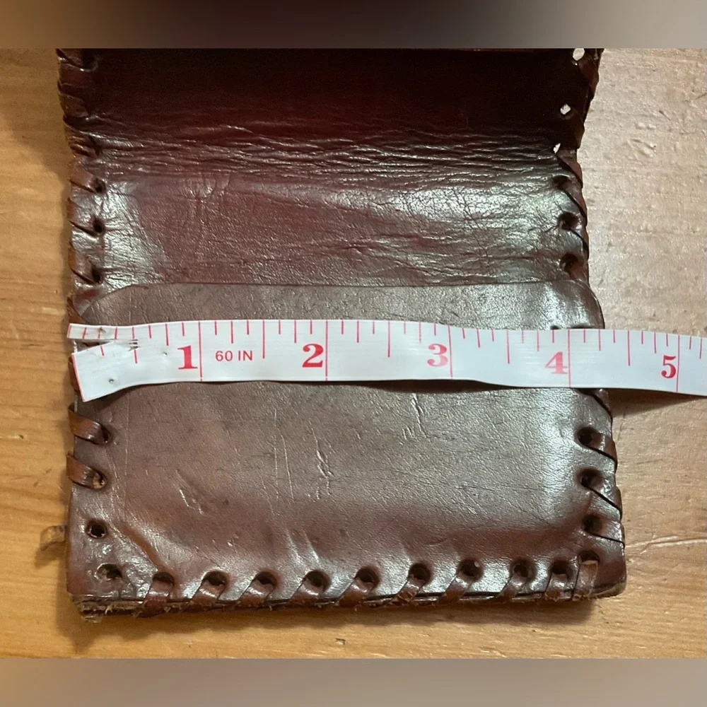 Hand crafted tooled mens leather design bifold wallet laced stitching around it.
